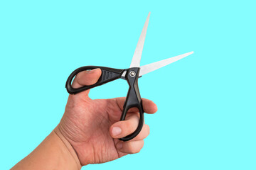 Hairdresser holding scissors for cutting hair or nails on blue background