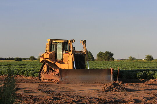 caterpillar bull dozer in a field ready for work with a crop in the background north of Hutchinson Kansas USA out in the country.