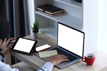 Over head shot of young male working with multiple electronic devices at home office.