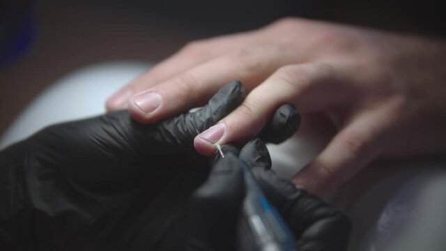 Male hardware manicure - the nail master using a small drill for manicure