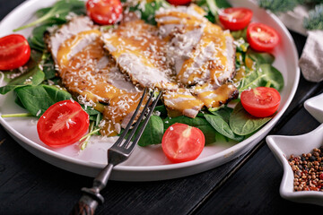 Close-up pork meat with sweet and sour sauce, spinach leaves, cherry tomatoes and grated cheese. Pan-Asian cuisine. Top view