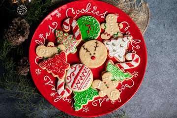 Red plate full of colorfully decorated Christmas cookies - Christmas eve recipes - Christmas holiday culinary traditions