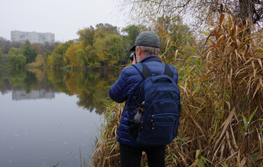 A man with a camera shoots a beautiful autumn landscape. Close-up. Selective focus.
