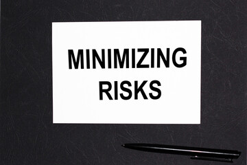 MINIMIZING RISKS.notebooks and a pen on the black table for information. . Business, marketing, financial concept