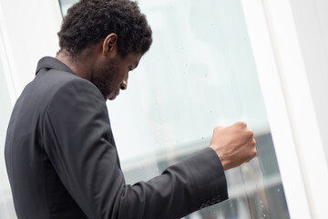 Fototapeta premium Angry upset African black businessman, portrait of failed unhappy black business man punching glass window, concept of work problem, office stress syndrome, economic recession, layoff, unemployment