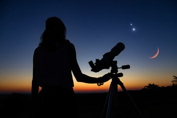 Woman looking at night sky with amateur astronomical telescope.