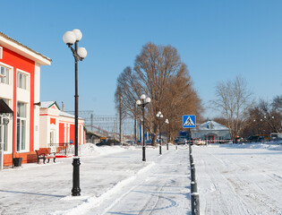 the territory of the station square in winter, cleared of snow area, pedestrian crossing lighting poles in a row