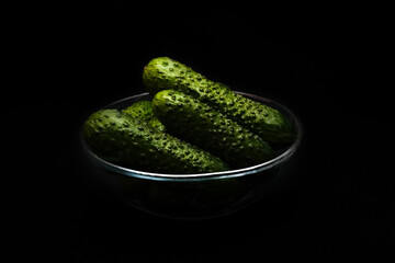 Cucumbers in glass bowl on dark background