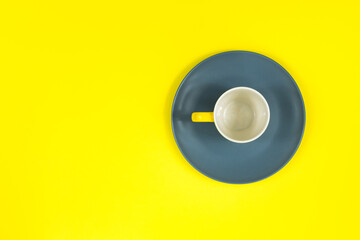 Cup on a gray plate on a yellow background. Place for an inscription.