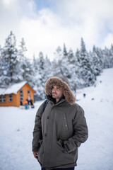 Hooded man with a snowy forest as background