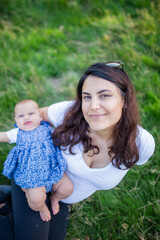 Happy woman sitting on the grass with her baby