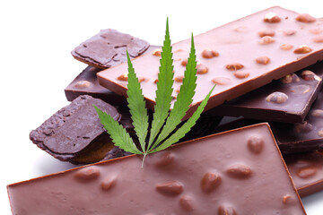 Chocolate with marijuana extract, chocolate biscuits with CBD content. Entertainment drugs concept. Chocolate bars with nuts and CBD cannabis content, green hemp leaf on white isolated background.
