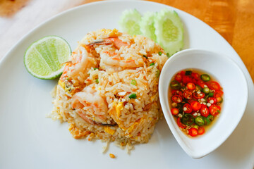 fried rice shrimp seafood lime and cucumber on plate wooden table from top view, thai food.