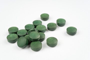 Spirulina tablets on white background. Nutrition, vitamin, immunity concept. Macro, copy space