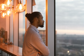 Pensive young African American man look in window distance thinking or planning career opportunities. Thoughtful biracial male lost in thoughts ponder or visualize. Business vision concept.