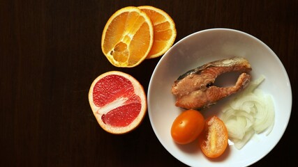a combination of the taste of red fish and citrus fruits in a ready-made dish of fried chum salmon steak seasoned with grapefruit and orange juice, sliced from half rings of onions and yellow tomatoes