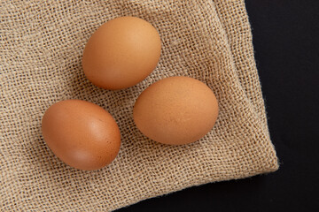 Fresh chicken eggs on burlap sack, top view.