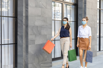 Two young ladies wearing face masks enjoy shopping during vacation. Modern lifestyle in new normal to prevent COVID-19 infection..