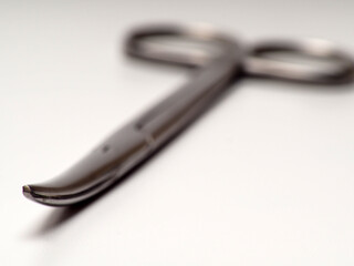 Close up shot of curved stainless steel medical scissor on an isolated white background