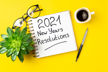 New year 2021 goals on desk. 2021 goals with open notebook, coffee cup, eyeglasses, plant succulent...