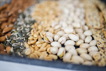 Black tray of nuts and seeds above a white table