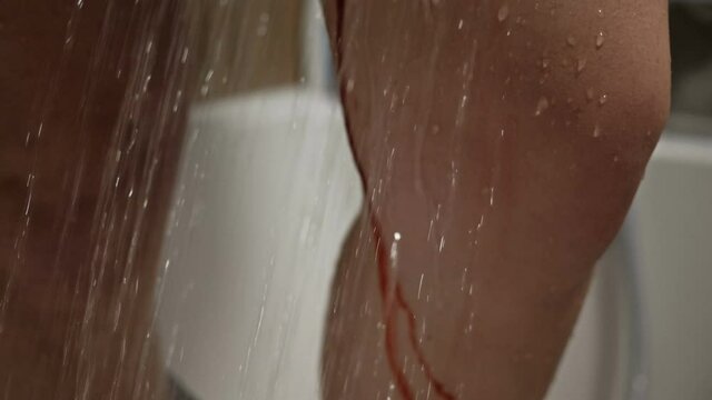Women's feet in the shower. The water washes away the blood. Spontaneous miscarriage in the early stages.
