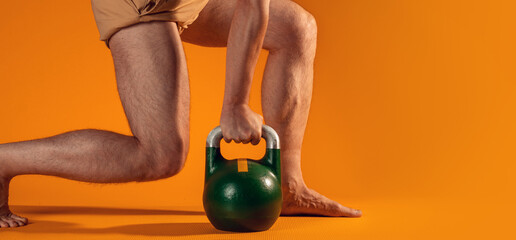 Muscular men's legs in a squat and a kettlebell in the hands,
