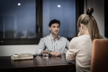 sad woman is sitting in front of her boss at work in a depressing atmosphere