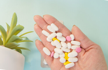 A handful of medical pills in the palm of your hand for the treatment of diseases, a WOMAN's HAND ON a BLUE BACKGROUND