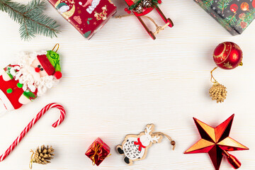 sleigh of santa claus, christmas tree branch, christmas toys, pine cone and boxes with gifts on a white wood background