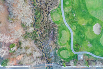 Above view of a green field next to an autumn forest