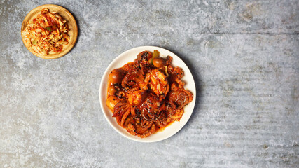 Fried squid with Korean spicy sauce on gray concrete table.