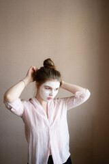 girl in a clay mask straightens her hair