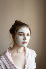 Girl in a white clay mask on her face
