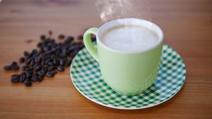 A green cup of Cappuccino with frothy foam, smoke and coffee bean