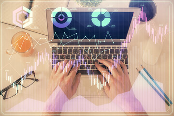 Double exposure of man's hands typing over laptop keyboard and forex chart hologram drawing. Top view. Financial markets concept.