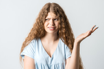 Studio shot of frustrated female gesturing with raised palm, frowning, being displeased and confused with dumb question.