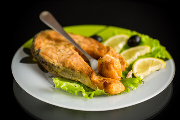 piece of fried salmon fish in a plate with lemon