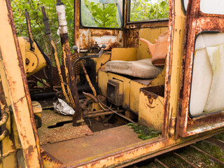 Fototapeta na wymiar Interior of cabin with lever, joystick and seat of abandoned deserted old rusty bulldozer, vintage industrial heavy machine, earthmover equipment, tracked vehicle