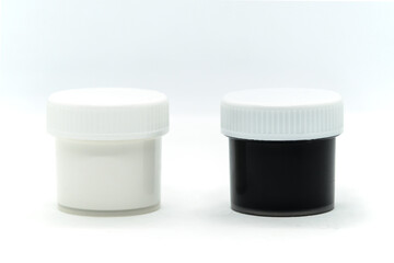 Closed plastic jars with gouache paint of black and white colors for painting on white background. Materials for drawing, calligraphy lessons