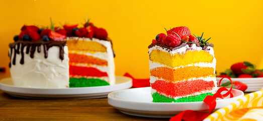 Rainbow cake banner with fresh berries on yellow background.
