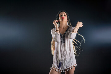 Attractive female feminist waring tribal short white dress. The isolated photo on a black background. Woman queen concept.