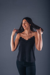 Female model dressed in black is posing in a studio