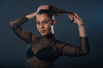 Fashion portrait of an attractive brunette girl holding and pulling her ponytail.