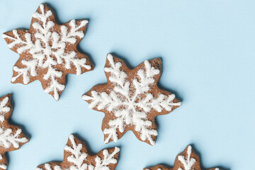 Star shaped gingerbread cookies on light blue wintery background.