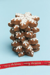 Star shaped gingerbread cookies with red festive ribbon on light blue  background.