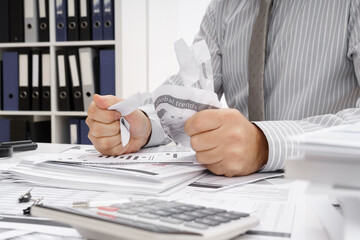 business problem concept - disappointed businessman has trouble and tears up reports