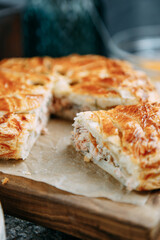 Salmon pie with puff pastry on a wooden background. Sliced fish pie close-up.