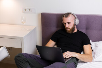 Man in bedroom on bed fell asleep in front of laptop 