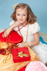 Beautiful young girl in an elegant dress with a red gift